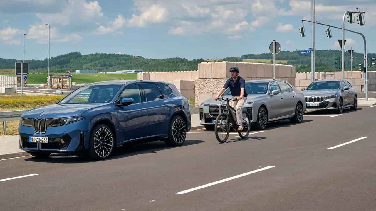 2027 BMW iX3 parked beside a bike lane with its exit-warning safety system highlighted
